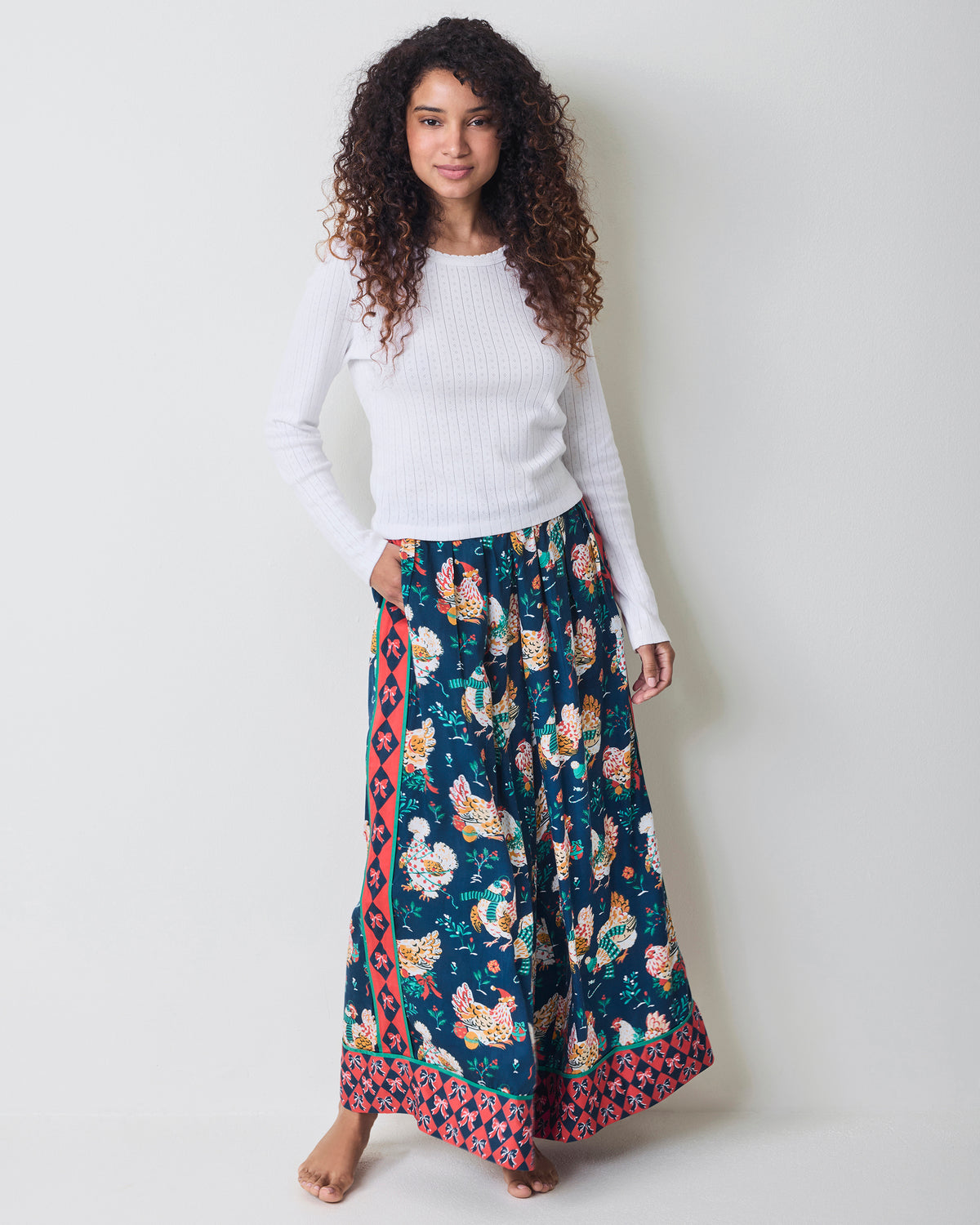 Full-length view of navy chicken-print wide-leg pajama pants worn with a white long-sleeve top.