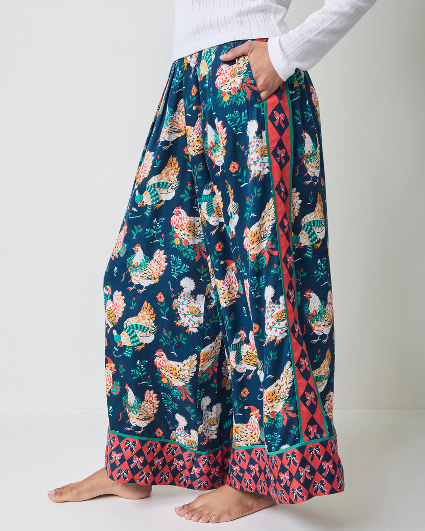 Side view of navy chicken-print wide-leg pajama pants showing the side pocket, waistband, and contrasting patterned cuffs.