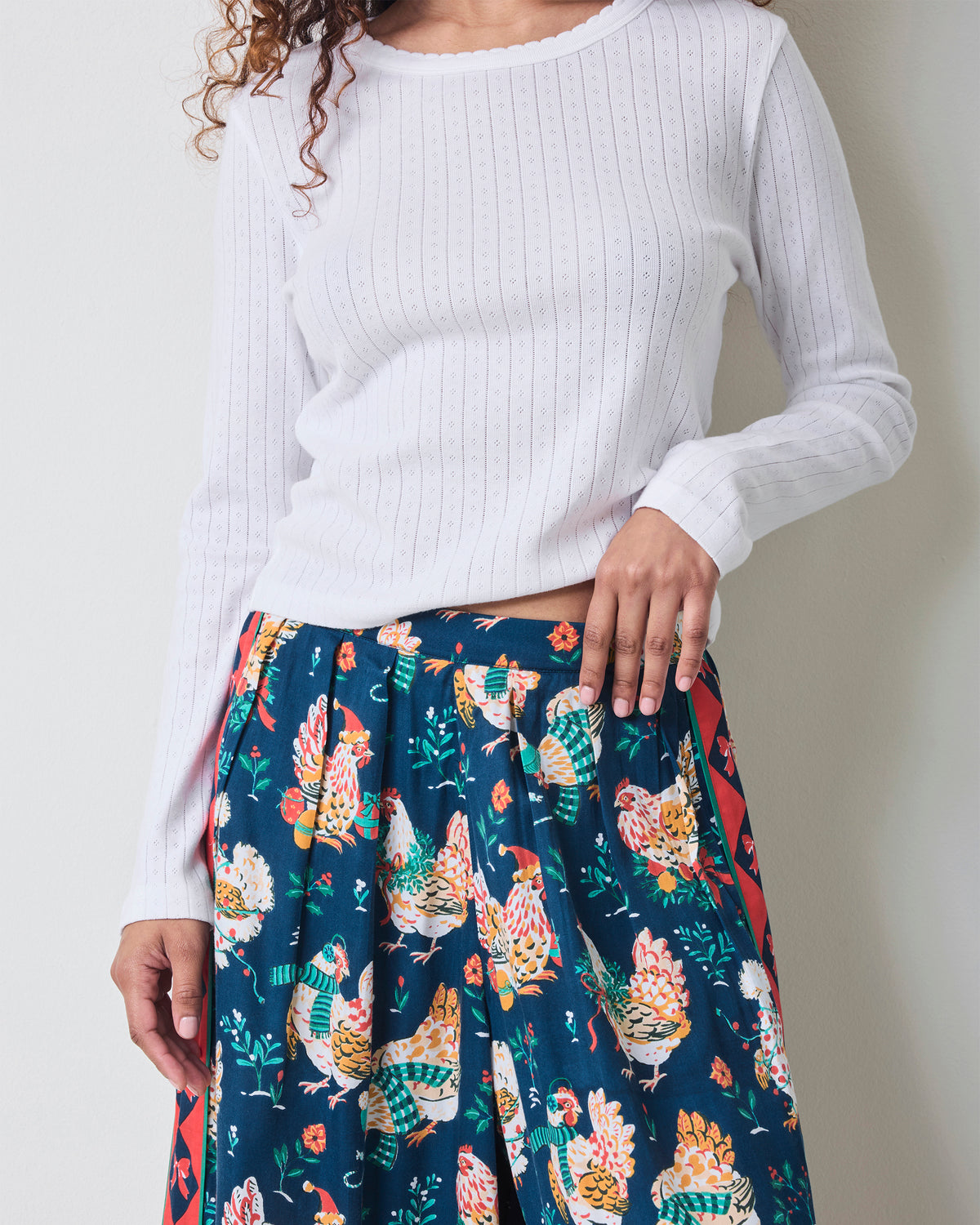 Close-up of the waistband and upper leg of navy chicken-print wide-leg pajama pants, with a side pocket visible.