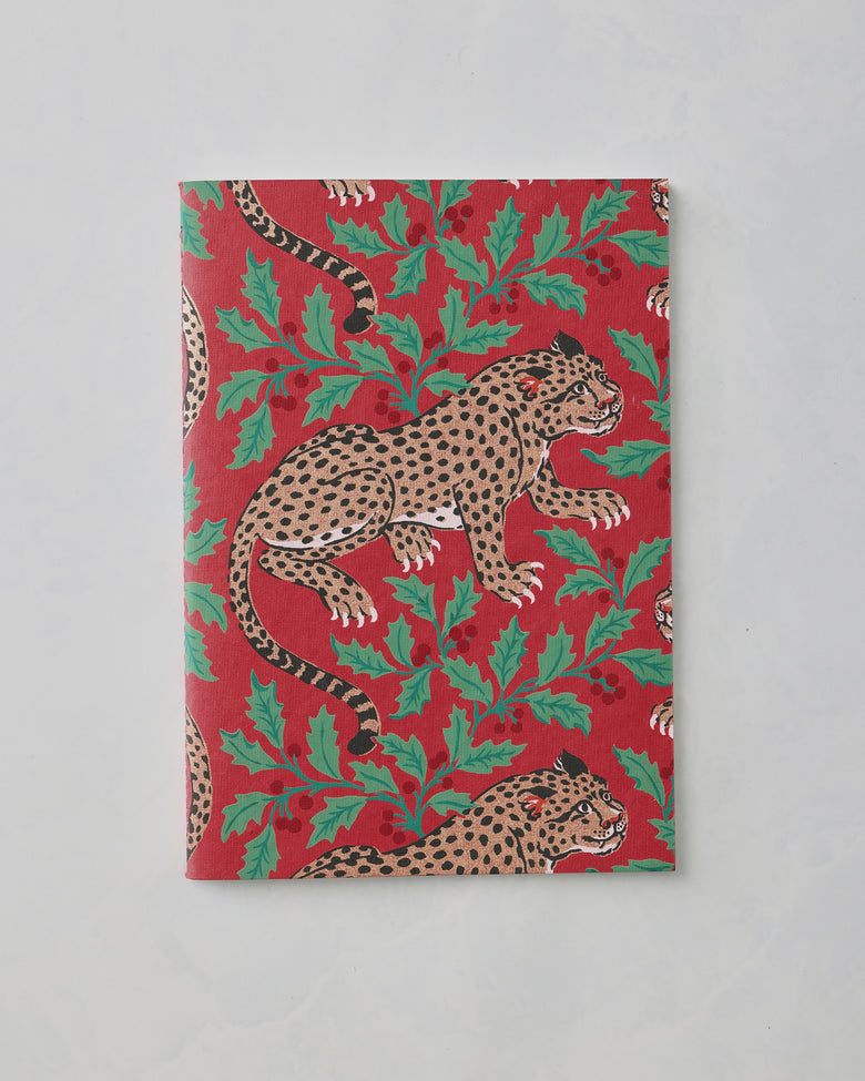 Closed red notebook with a repeating leopard and leafy print.