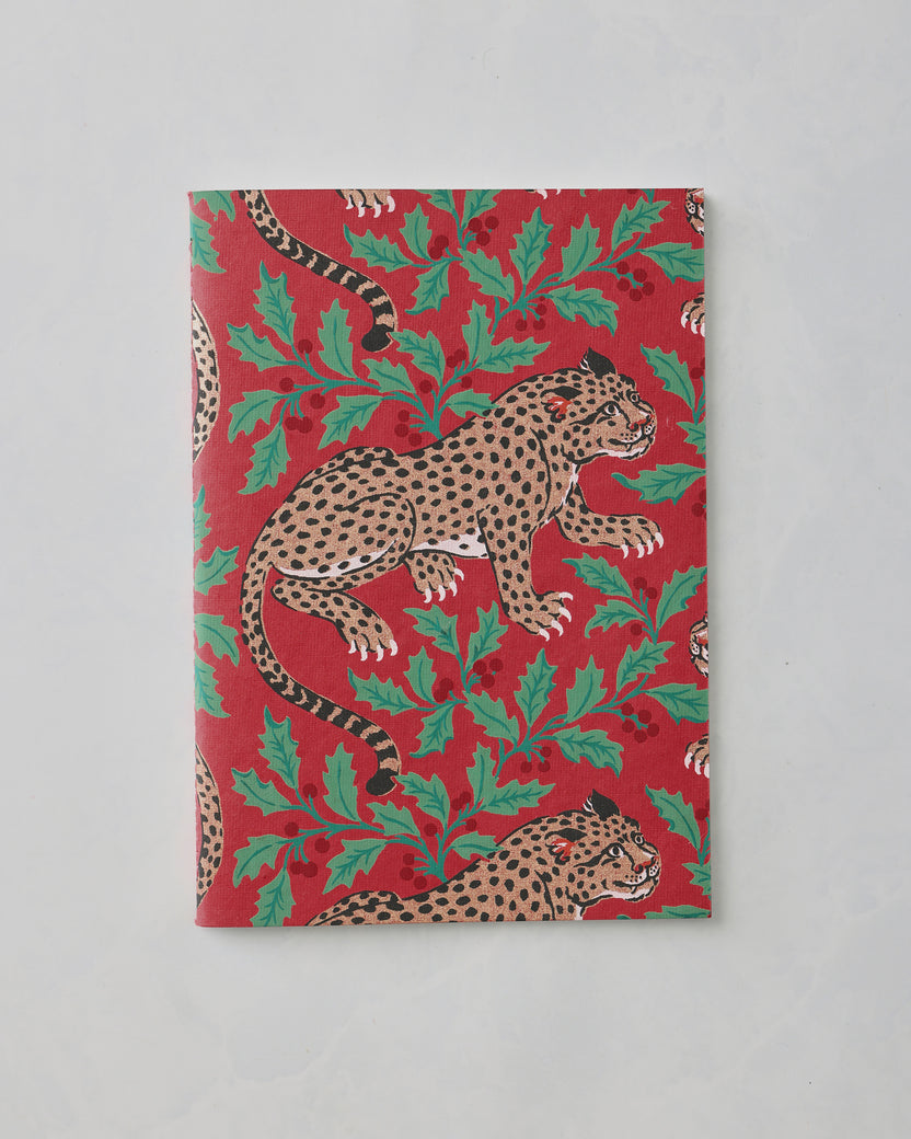 Closed red notebook with a repeating leopard and leafy print.