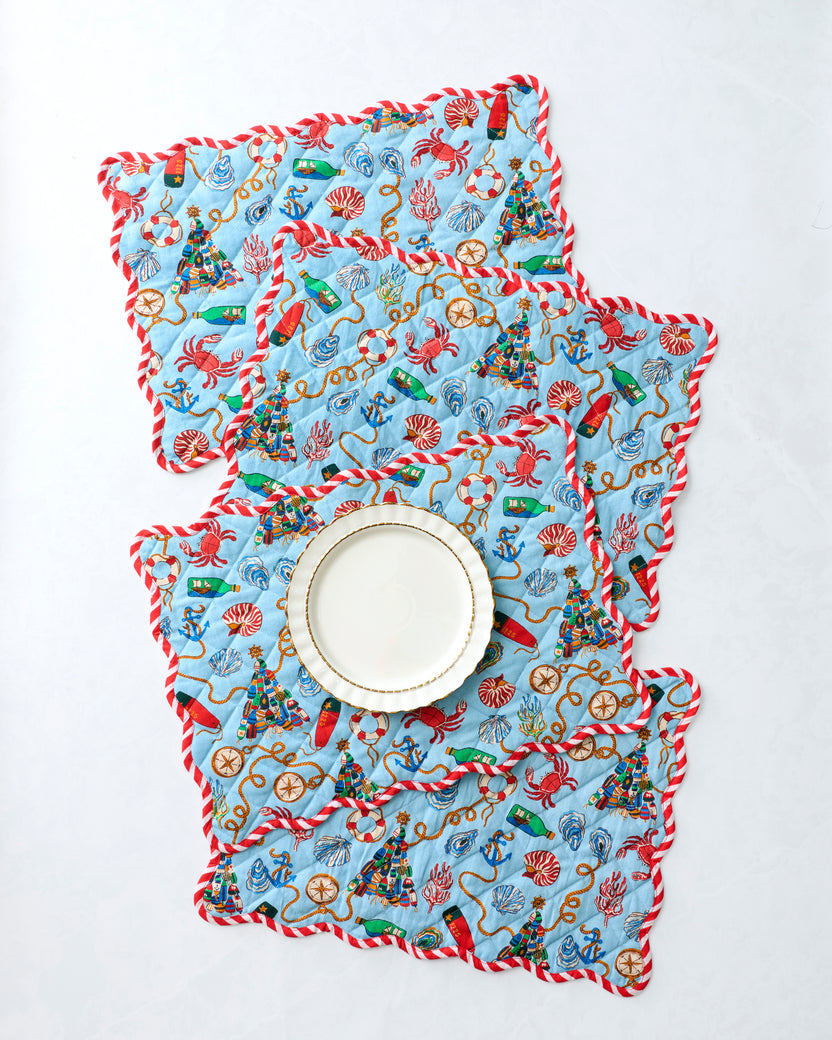 Four nautical-print placemats arranged with a plate on a white surface.