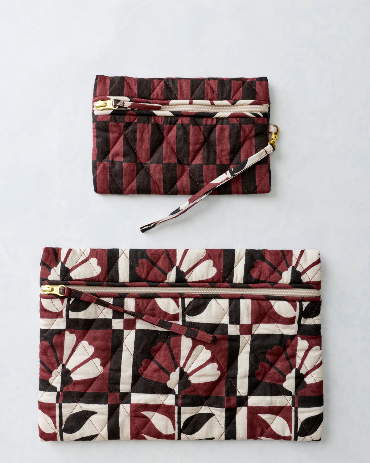 Two quilted zippered pouches shown separately, with the smaller pouch above the larger floral-print pouch.