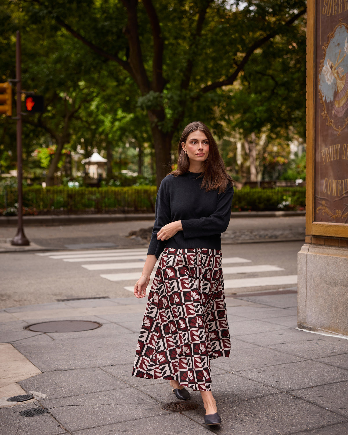 Full-length outdoor view of a model wearing the Bordeaux Sparrow Skirt with a black long-sleeve top and black flats.
