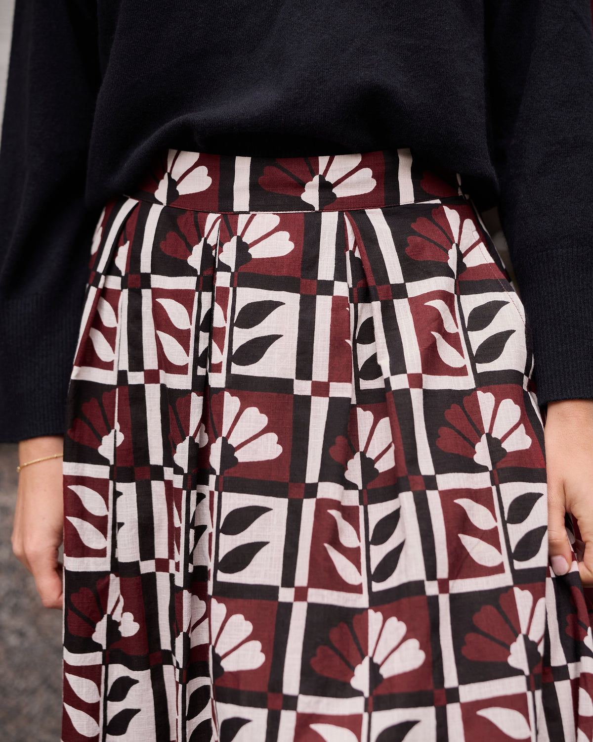 Close-up of the Hygge Greenhouse Sparrow Skirt showing its waistband, pleats, pockets, and repeating floral geometric print.