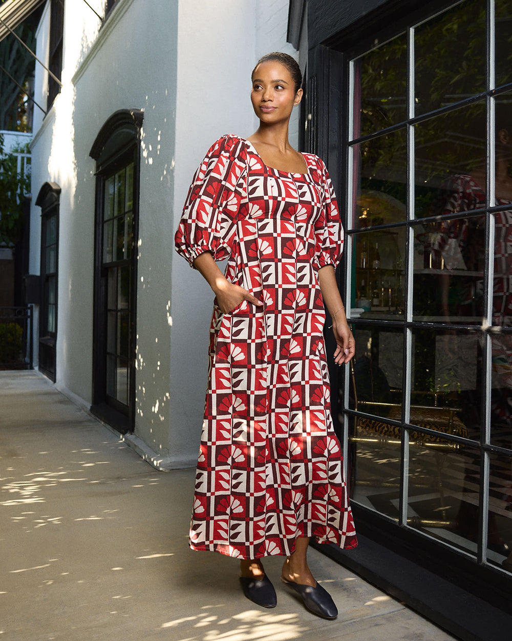 Front view of the Constance dress in a red-and-white floral geometric print, with puff sleeves and side pockets.