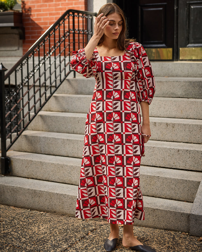 Person wearing the Poppy Hygge Greenhouse Constance dress, a red-and-white patterned midi dress with three-quarter puff sleeves.