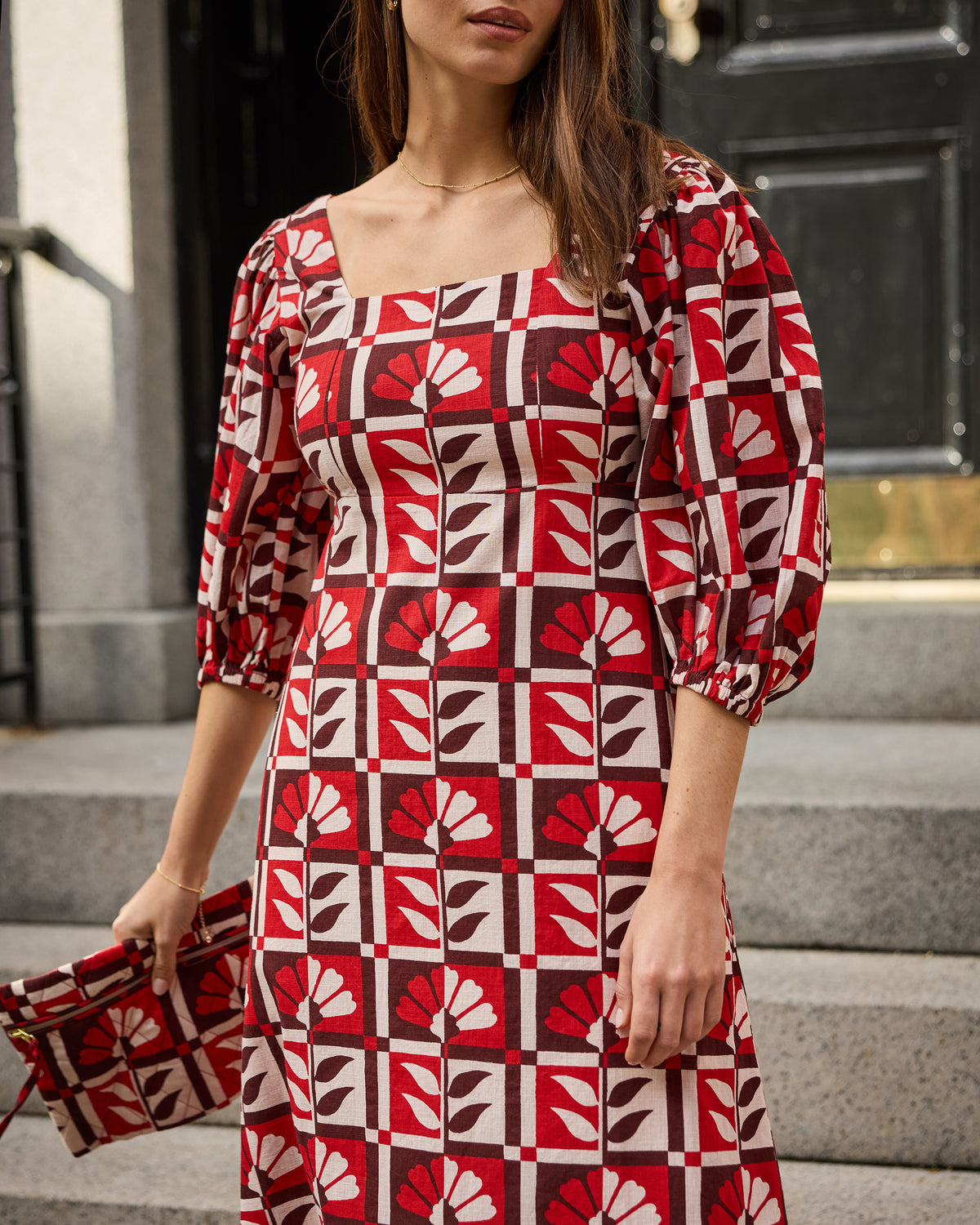 Close front view of the Constance dress showing its square neckline, puff sleeve, and red-and-white floral geometric print.