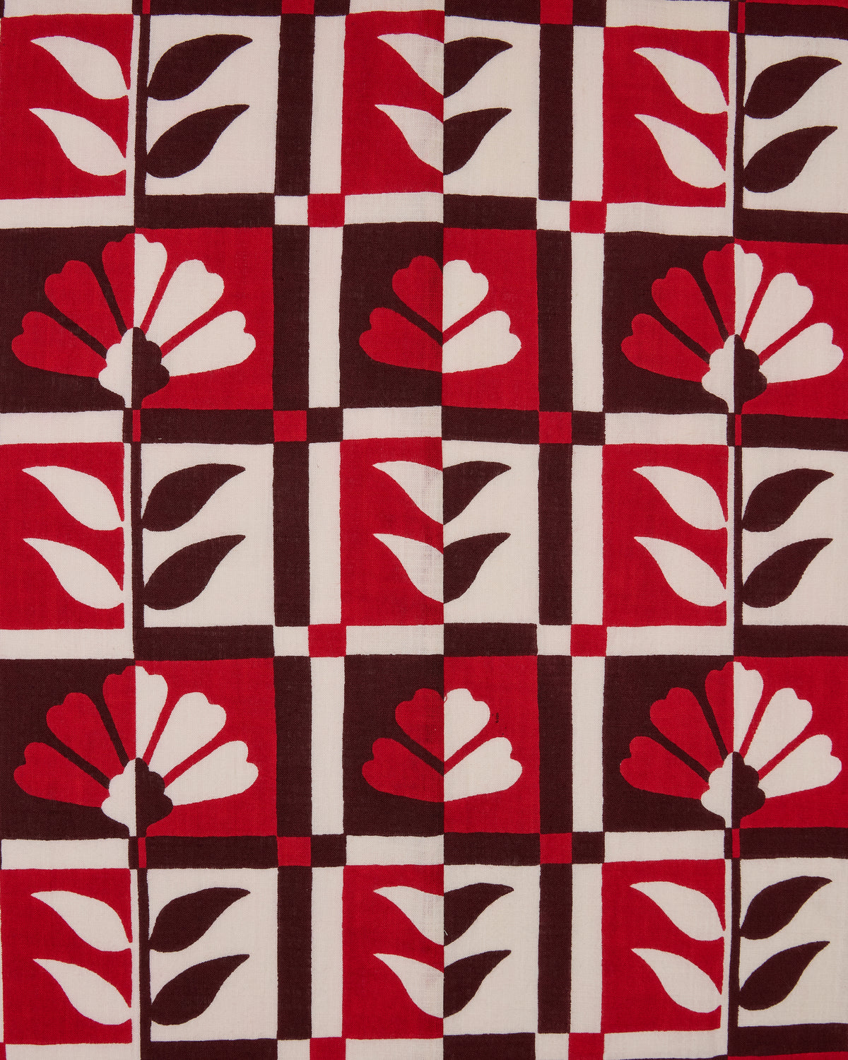 Hygge Greenhouse pattern swatch with stylized flowers and leaves in red, cream, and dark brown geometric blocks.