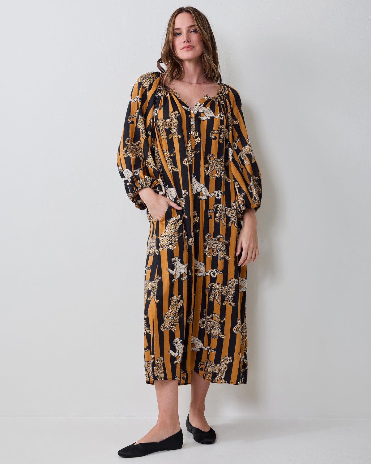Front view of a butterscotch-and-black striped Felicity dress with leopard illustrations, long sleeves, and side pockets.