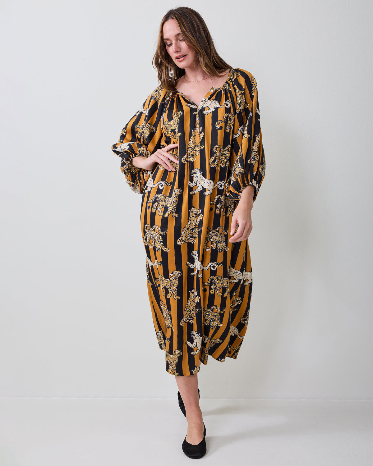 Three-quarter front view of the Leopard Stripes Felicity dress showing the V-neckline, gathered sleeves, waist tie, and midi-length skirt.
