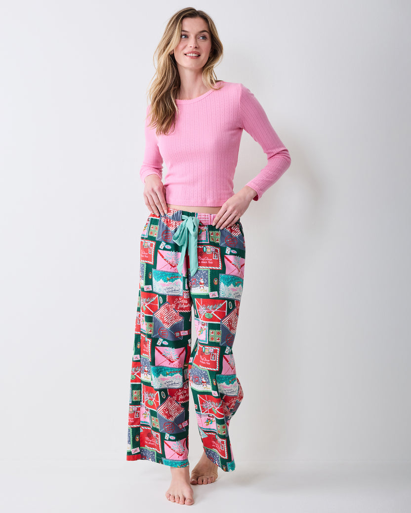 Front view of Letters to Santa Astrid pants with a mint drawstring and colorful postcard print, styled with a pink ribbed top.