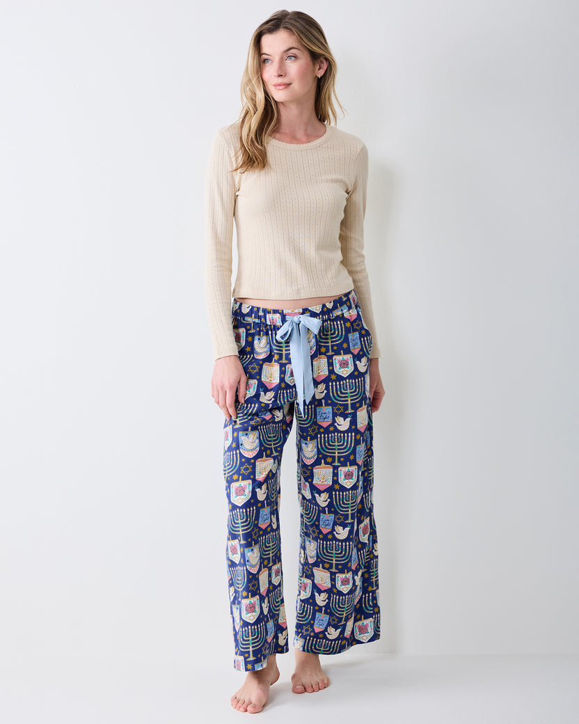 Full-length view of Hanukkah Blue Love & Light pants with a dark blue menorah, dreidel, dove, and star print, elastic waistband, and drawstring.