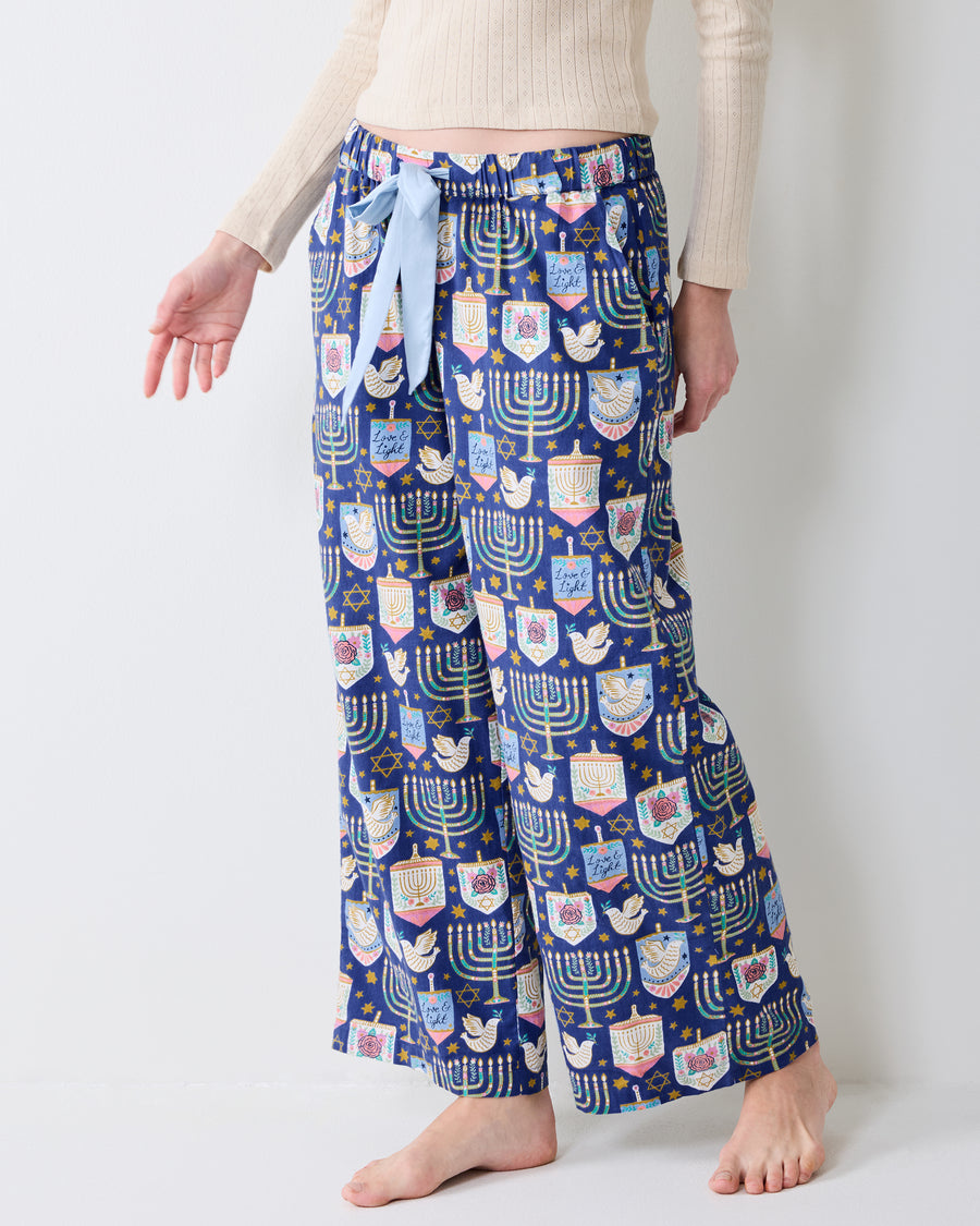 Three-quarter rear view of Hanukkah Blue Astrid wide-leg pajama pants, showing the repeating menorah and holiday print.