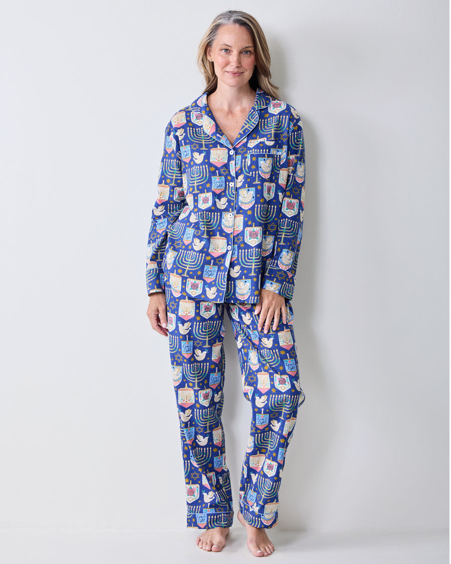Person wearing a blue long-sleeve pajama set with menorah, dreidel, and Star of David prints