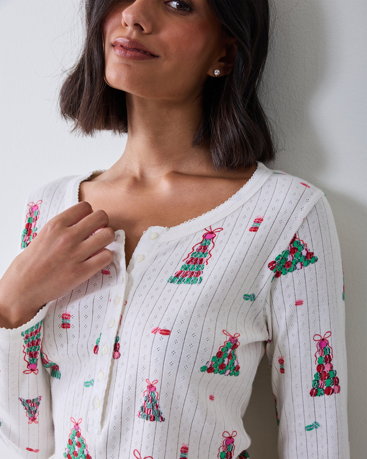 Close-up of the Macaron Tower knit pajama top showing its lace-trimmed neckline, buttons, and holiday tree print.