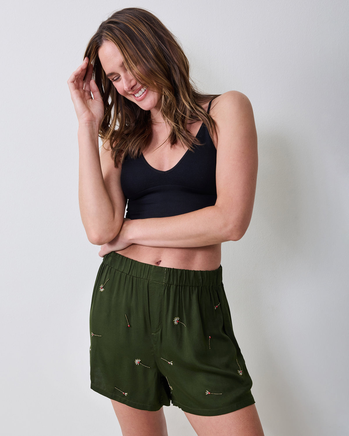 Model wearing olive embroidered boxer shorts with a black sleeveless top, shown from the front.