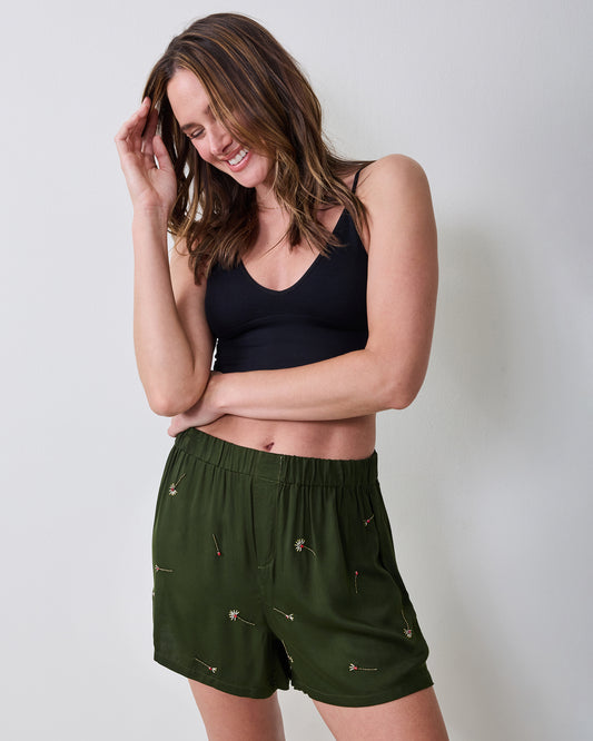 Model wearing olive embroidered boxer shorts with a black sleeveless top, shown from the front.
