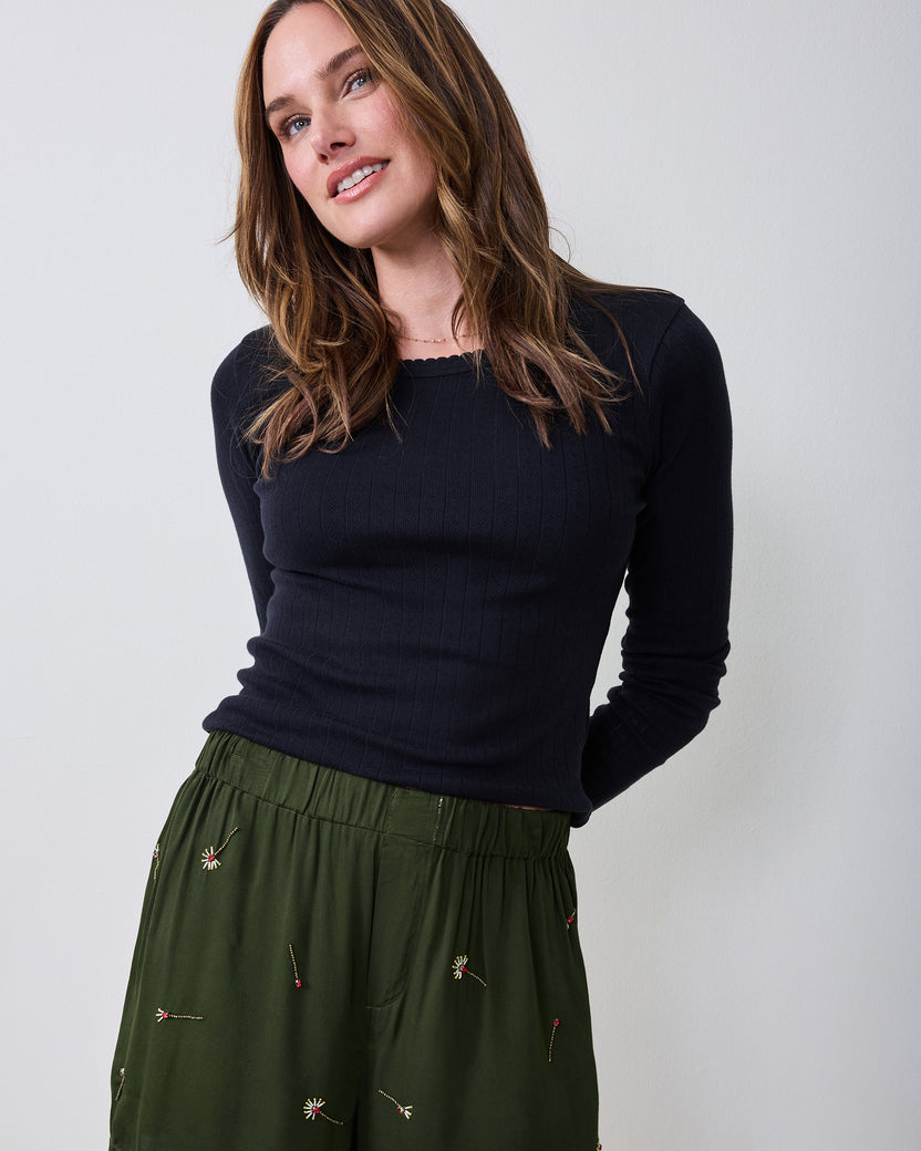 Front view of olive embroidered boxer shorts worn with a black long-sleeve top.