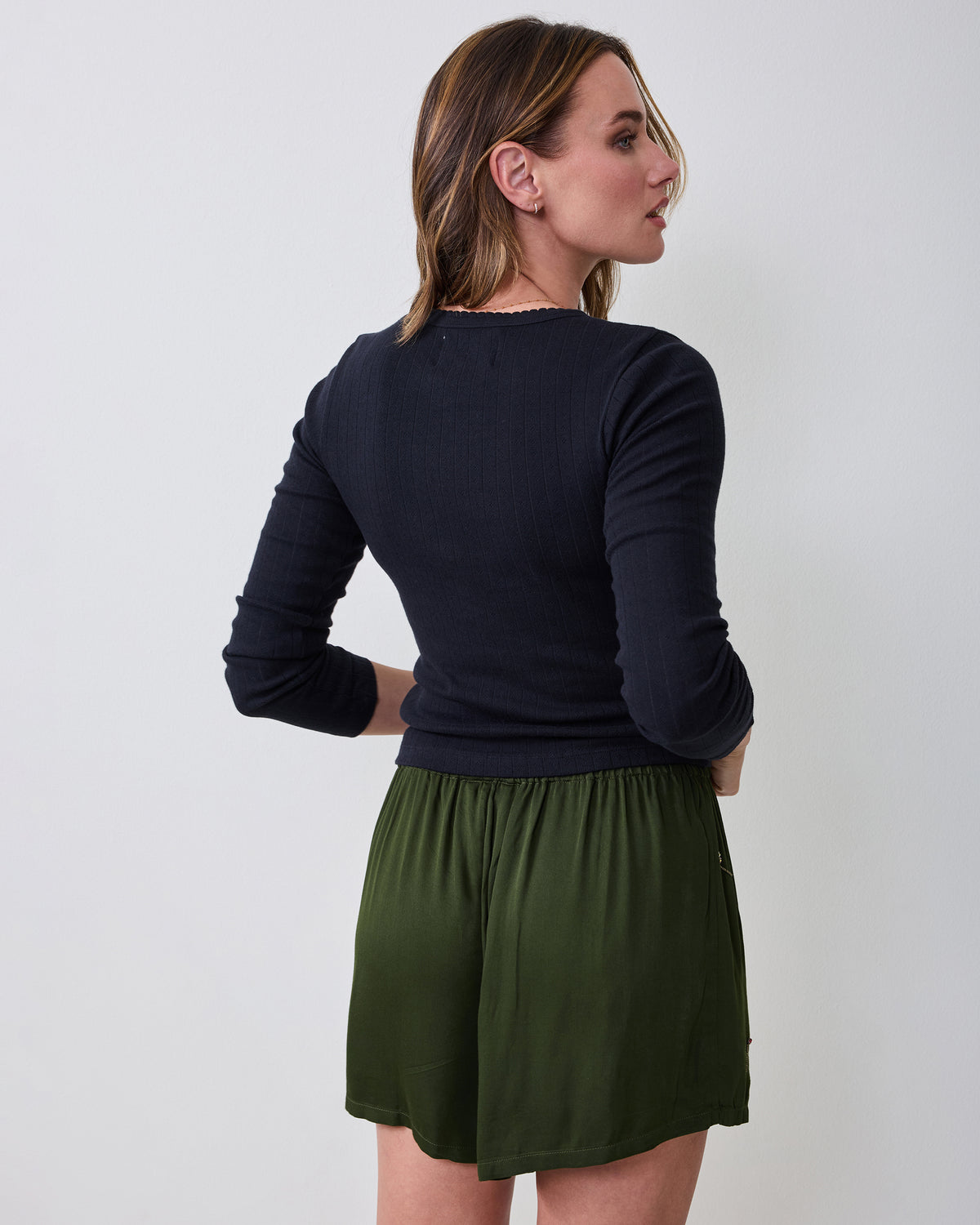 Back view of a person wearing olive boxer shorts with an elastic waistband.