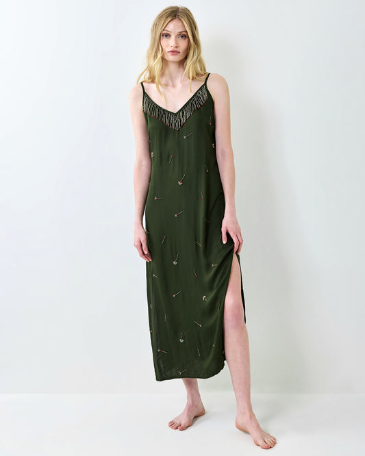 Full-length front view of an olive slip dress with a beaded fringe neckline, embroidered match motifs, and a side slit.