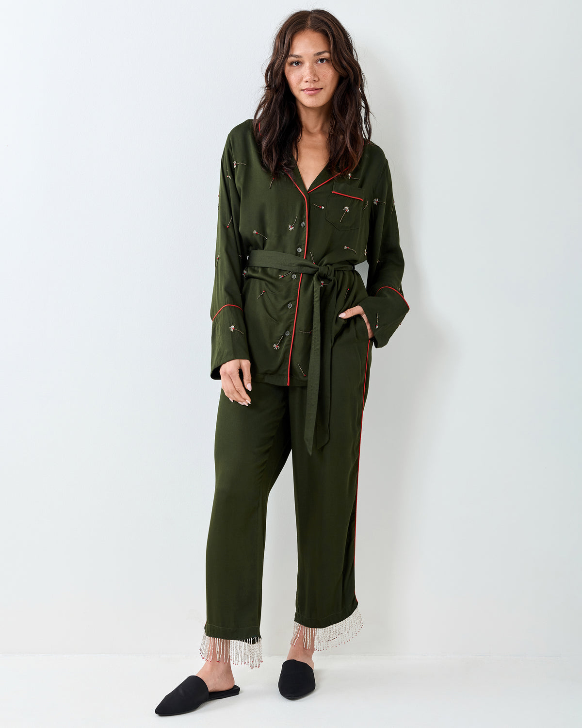 Front view of the olive Matchmaker pajama set with red piping, a belted button-front top, cropped pants, and fringe at the hems.