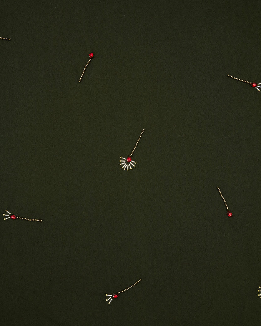 Close-up of the olive fabric featuring scattered embroidered red-and-gold motifs.