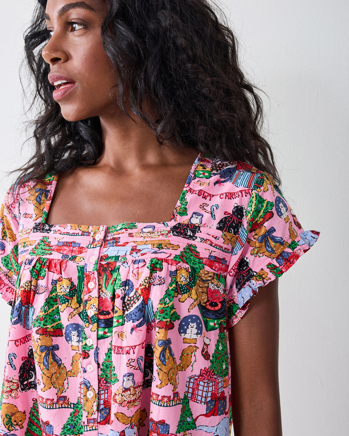 Person wearing the candy-pink Meowy Christmas pintuck nightgown with short sleeves, buttons, a ruffled neckline, and a festive cat print.