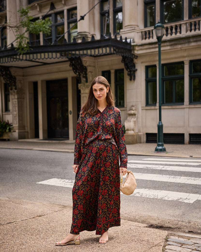Full view of the garnet Sasha pants worn with a matching floral blouse, showing the wide legs and botanical print.