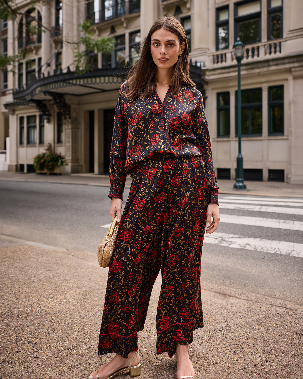 Front view of the garnet Sasha pants worn with a matching floral blouse, showing the wide legs and botanical print.