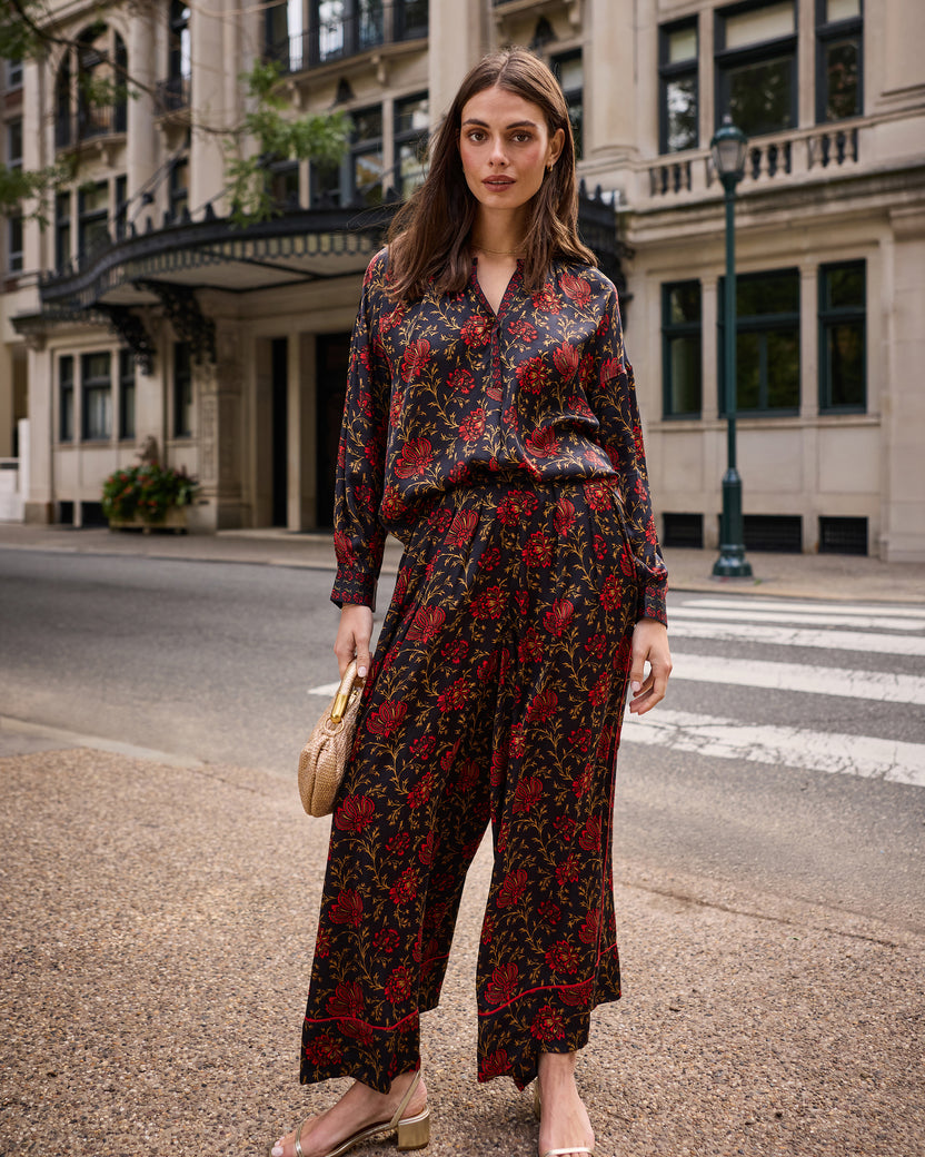 Front view of the garnet Sasha pants worn with a matching floral blouse, showing the wide legs and botanical print.
