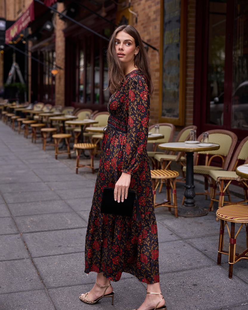 Model wearing the Midwinter Bloom Linnia dress with a dark floral print outside a café.
