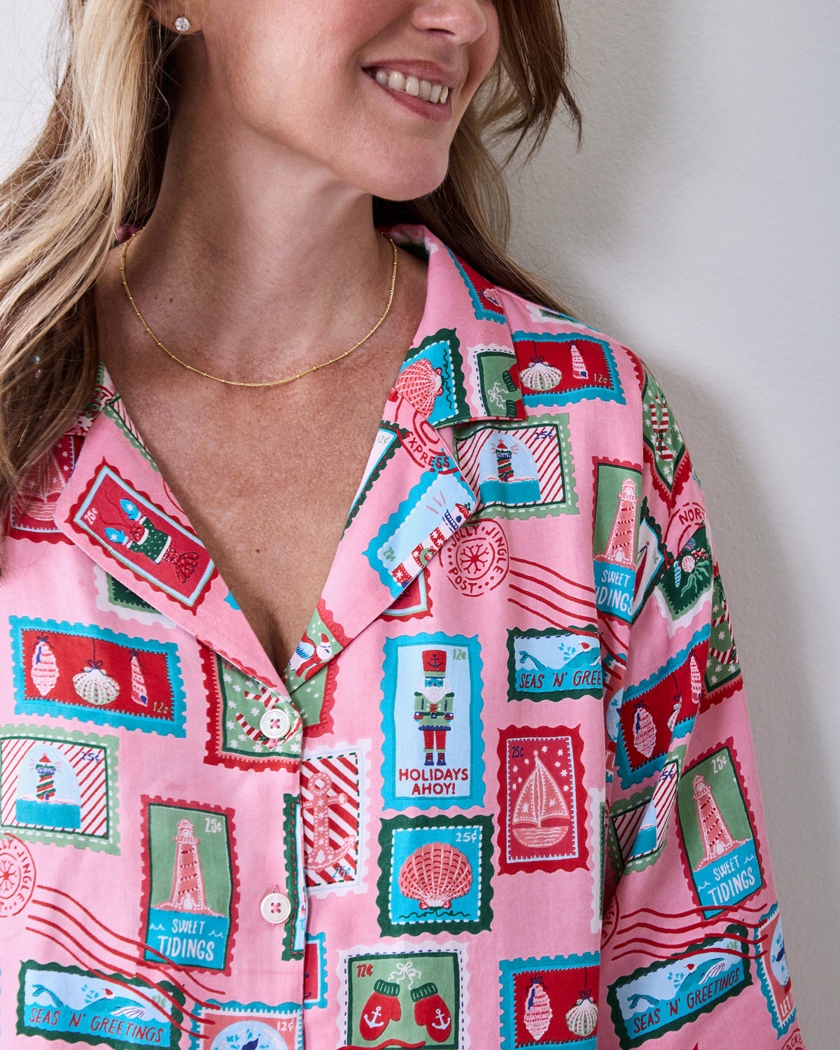 Close-up of a pink nautical-stamp print button-front top with short sleeves and white buttons.