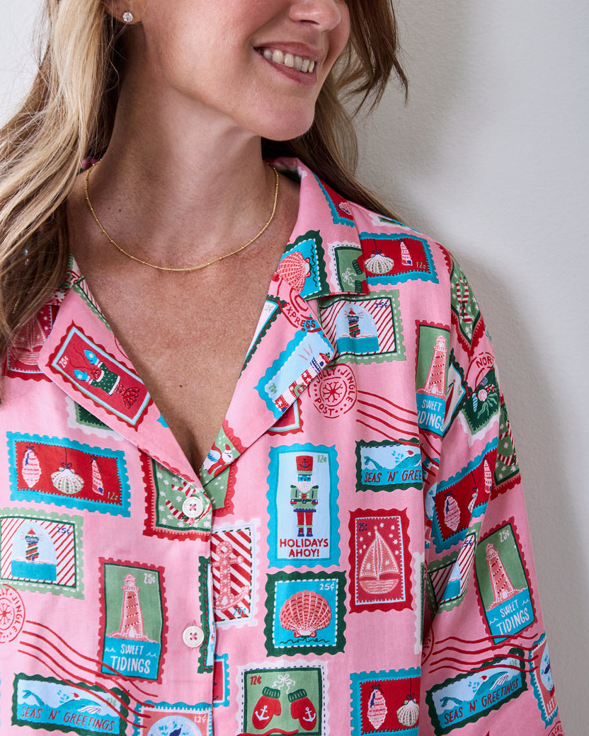 Close-up of a pink nautical-stamp print button-front top with short sleeves and white buttons.