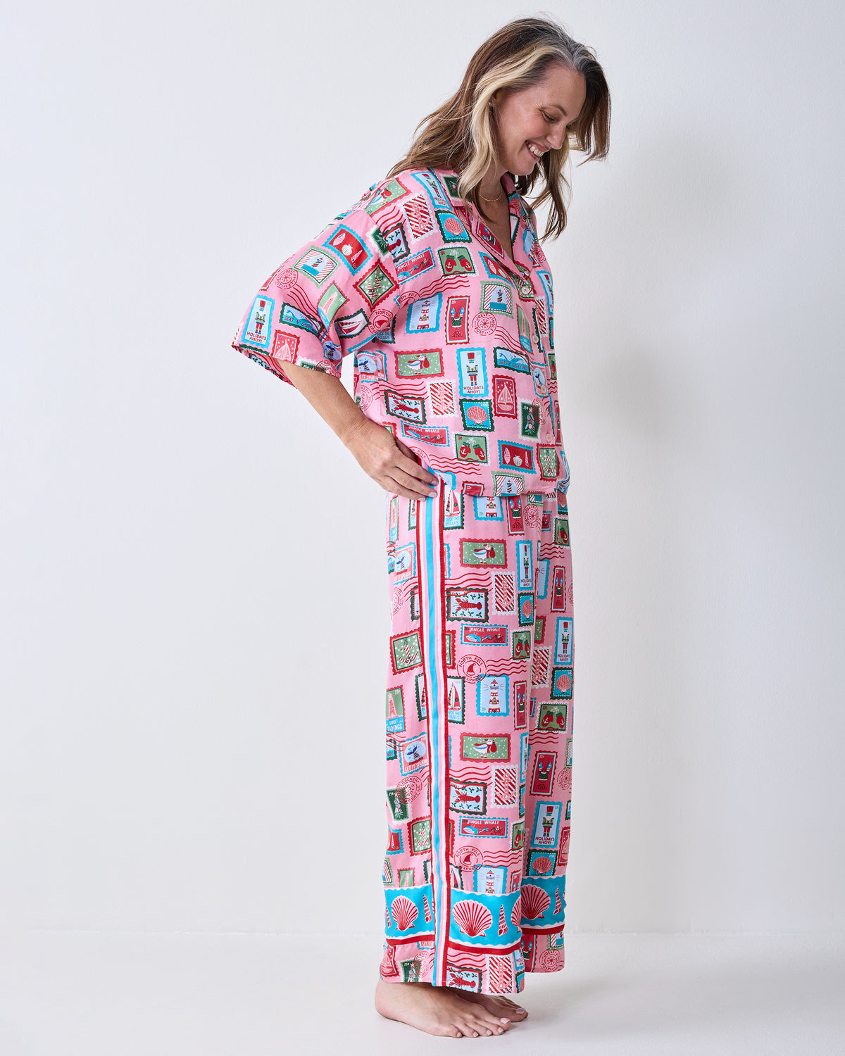 Side view of a model wearing the pink Nautical Stamps Eco Satin pajama set, showing the short-sleeved top and wide-leg pants.