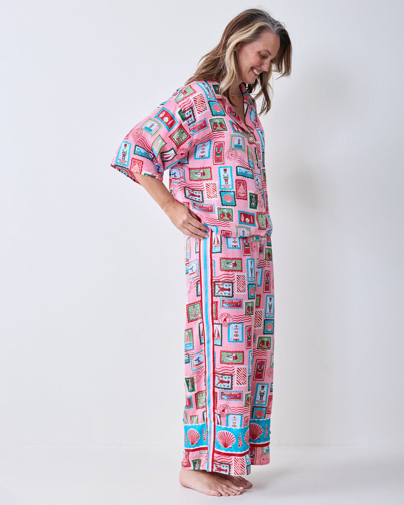 Side view of a model wearing the pink Nautical Stamps Eco Satin pajama set, showing the short-sleeved top and wide-leg pants.