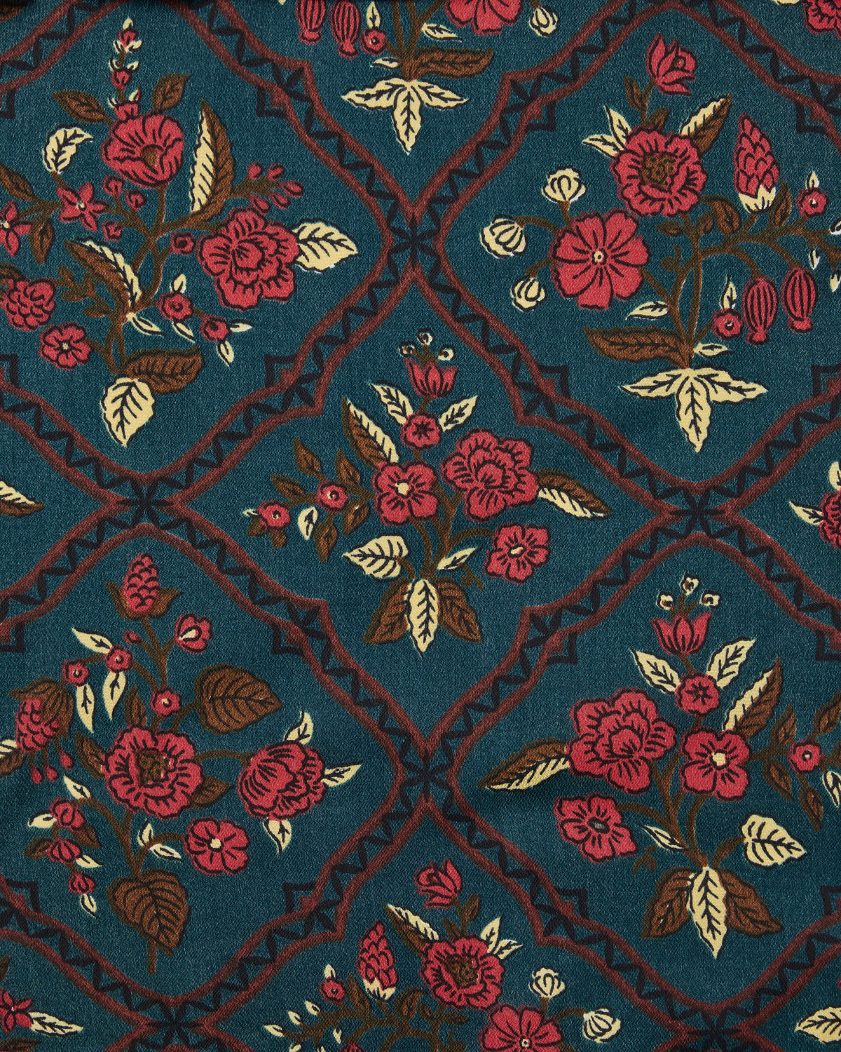 Close-up swatch of the Nordic Garden print with red and cream flowers inside geometric diamond motifs on a teal background.