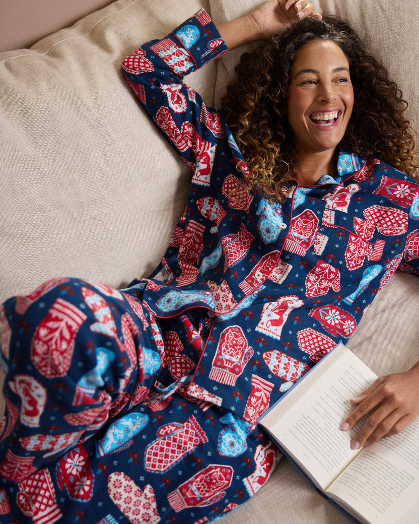 Person reclining on a bed wearing the Nordic Mittens Viking Blue long pajama set and holding an open book.