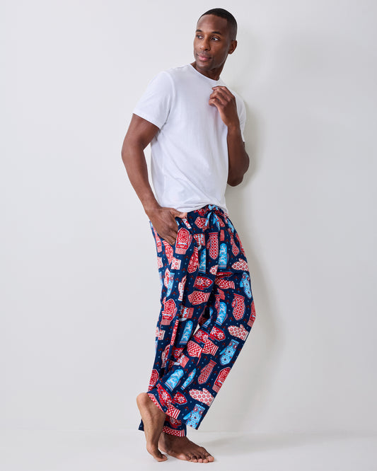 Side view of blue flannel men's pajama pants with a red, white, and light blue mitten print, worn with a white T-shirt.