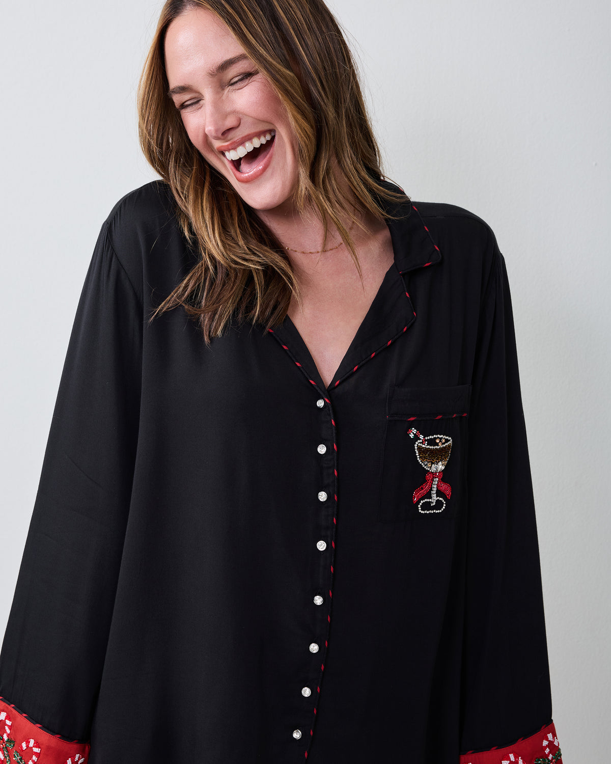 Close view of the black pajama shirt with red-trimmed piping, silver buttons, and martini-glass embroidery on the chest pocket.