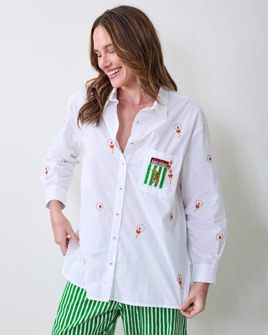 Person modeling the white RSVP button-down shirt with red-and-gold motifs, a green pocket patch, and green-and-white striped pants.