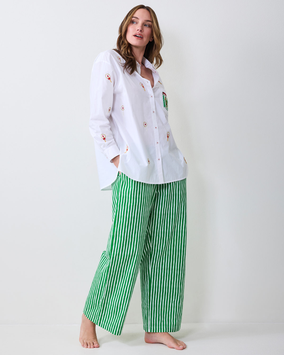 Model wearing a white embroidered button-down shirt and green-and-white striped wide-leg pajama pants.