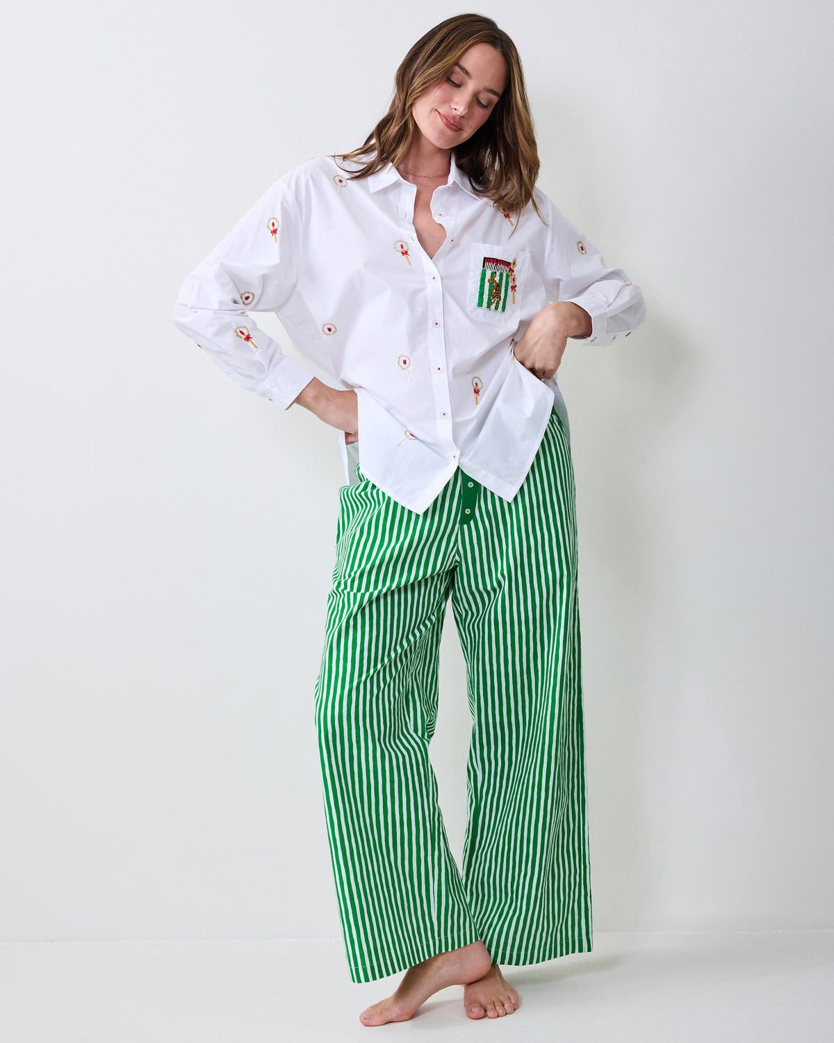 Person modeling the white RSVP button-down shirt with red-and-gold motifs and a green pocket patch, paired with green-and-white striped pants.