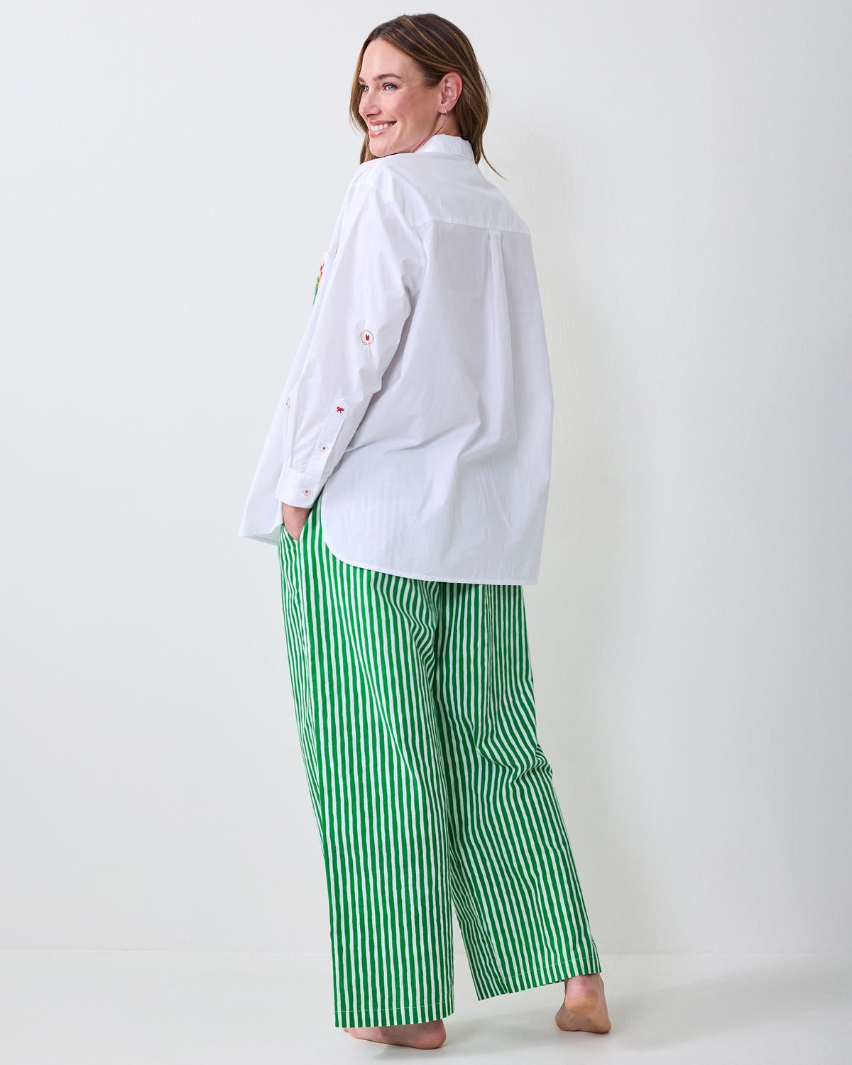 Back view of a white button-down shirt worn over green-and-white vertically striped pants.