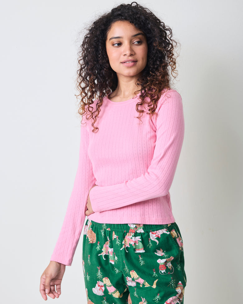 Front three-quarter view of the pink taffy long-sleeve pointelle top with scalloped neckline, paired with green patterned pajama pants.