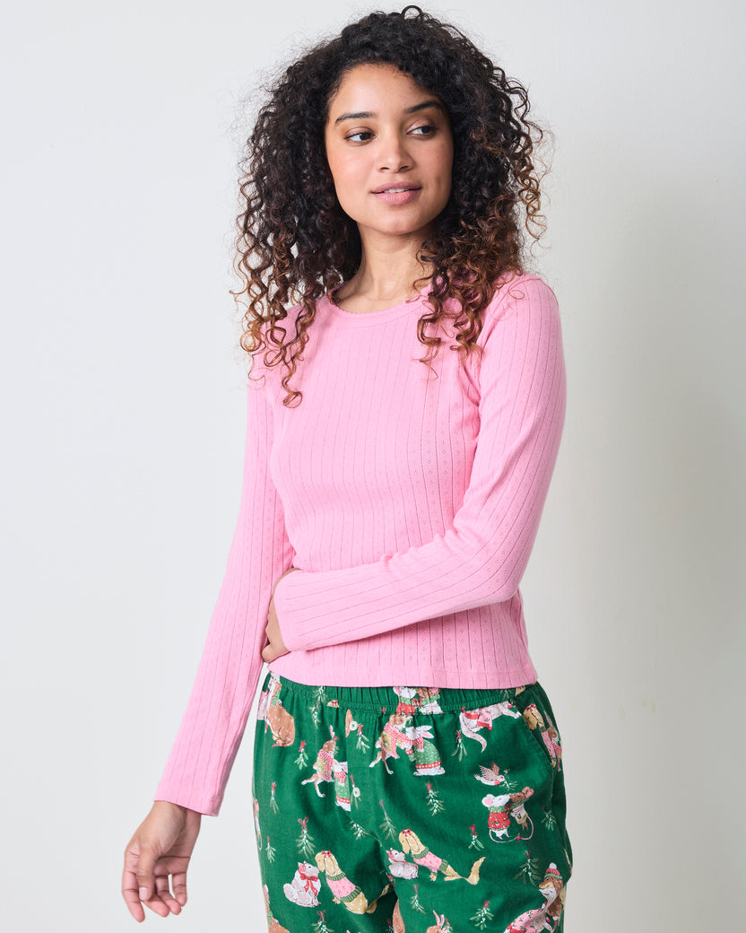 Front three-quarter view of the pink taffy long-sleeve pointelle top with scalloped neckline, paired with green patterned pajama pants.