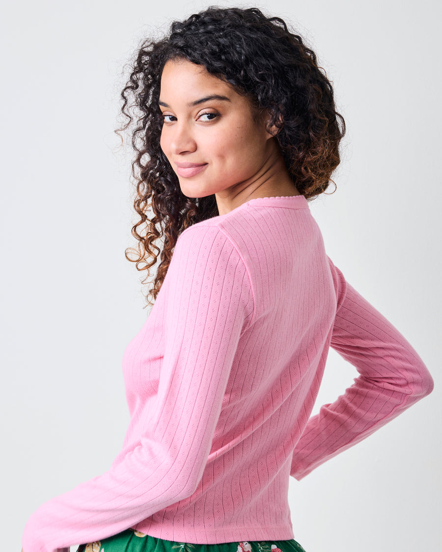 Back three-quarter view of the pink taffy long-sleeve pointelle top with green patterned pajama pants.