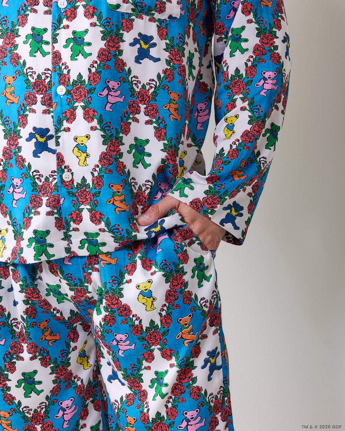 Close-up of the pajama top and pants showing the matching bear-and-rose print and a hand in the side pocket.