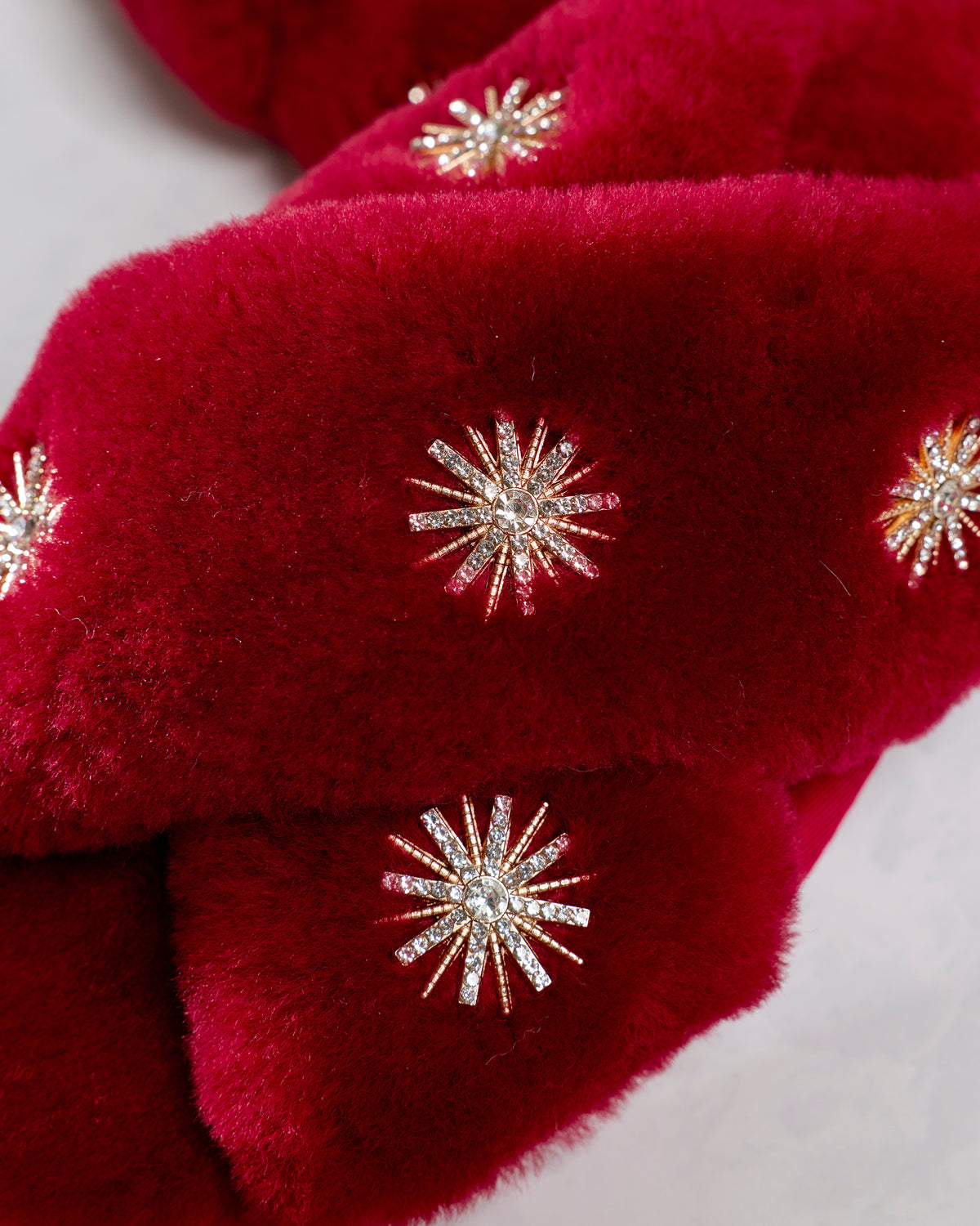Close-up of rhinestone starburst embellishments on wine sheepskin slipper uppers.