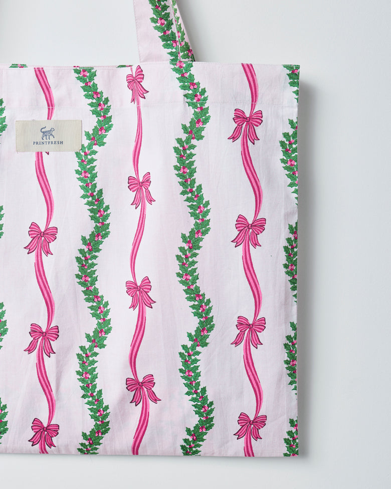 Vanilla cream tote bag with vertical pink ribbon bows and green floral garland stripes, shown from the front.